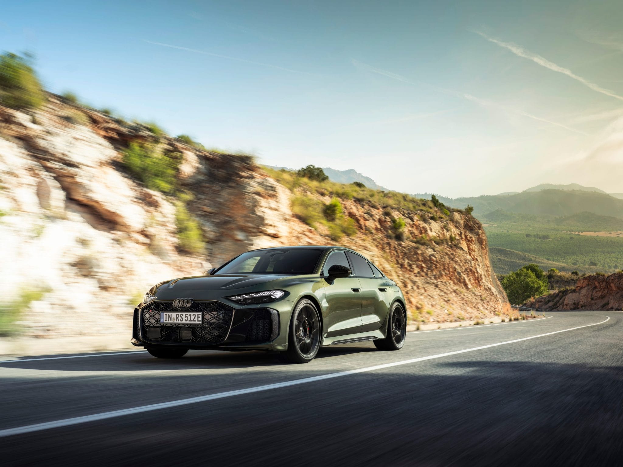 Matte green Audi RS5 driving on scenic mountain highway