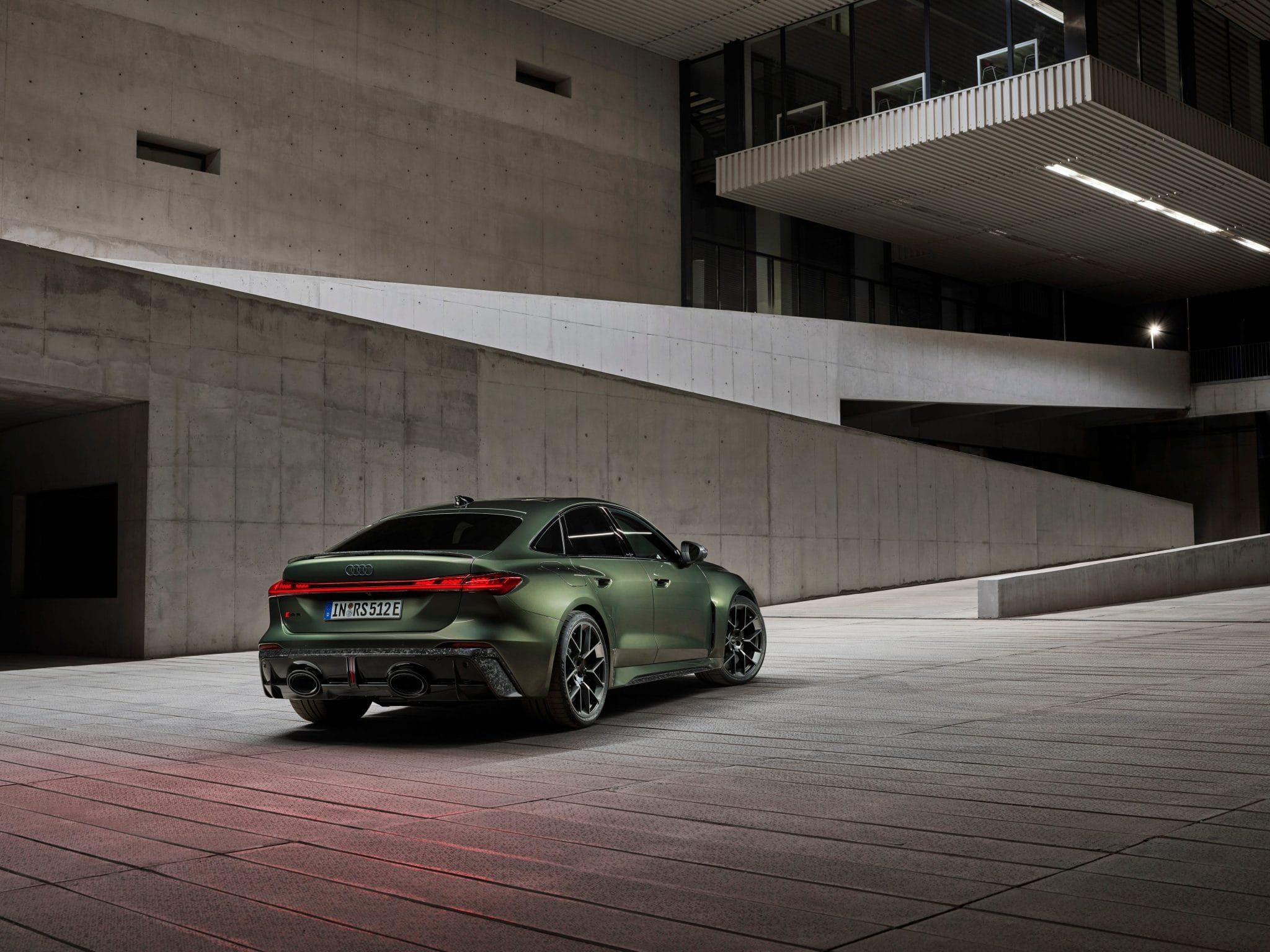 Matte green Audi RS5 Sportback rear view at modern architectural setting