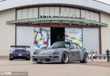 A slate gray Rauh-Welt Begriff 993-generation Porsche 911 parked in front of The Hangar building at the OC Fair & Event Center during Air | Water 2026, with a purple 992 GT3 RS visible in the background. Photo by Adam Hyatt for CarCultureTV.