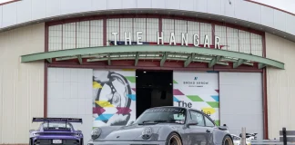 A slate gray Rauh-Welt Begriff 993-generation Porsche 911 parked in front of The Hangar building at the OC Fair & Event Center during Air | Water 2026, with a purple 992 GT3 RS visible in the background. Photo by Adam Hyatt for CarCultureTV.